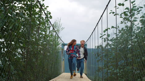 Fun-couple-running-nature-on-mountains-river-bridge.-Two-hikers-enjoy-trekking.