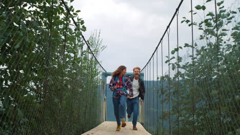 una pareja divertida corriendo por la naturaleza en el puente del río de las montañas. dos excursionistas disfrutan del senderismo.