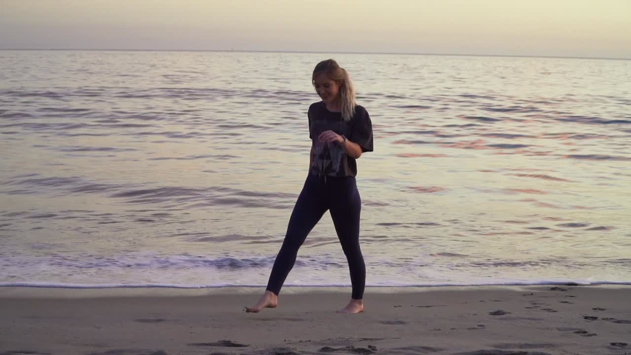 Blond kvinde løber væk fra bølgerne på stranden