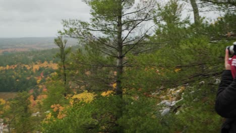 Man-with-Film-Camera-takes-Photo-at-Lookout-Cliff,-Wide-Handheld-Pan