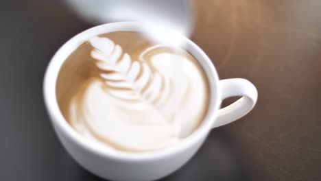 professional barista pouring milk into coffee cup making latte art