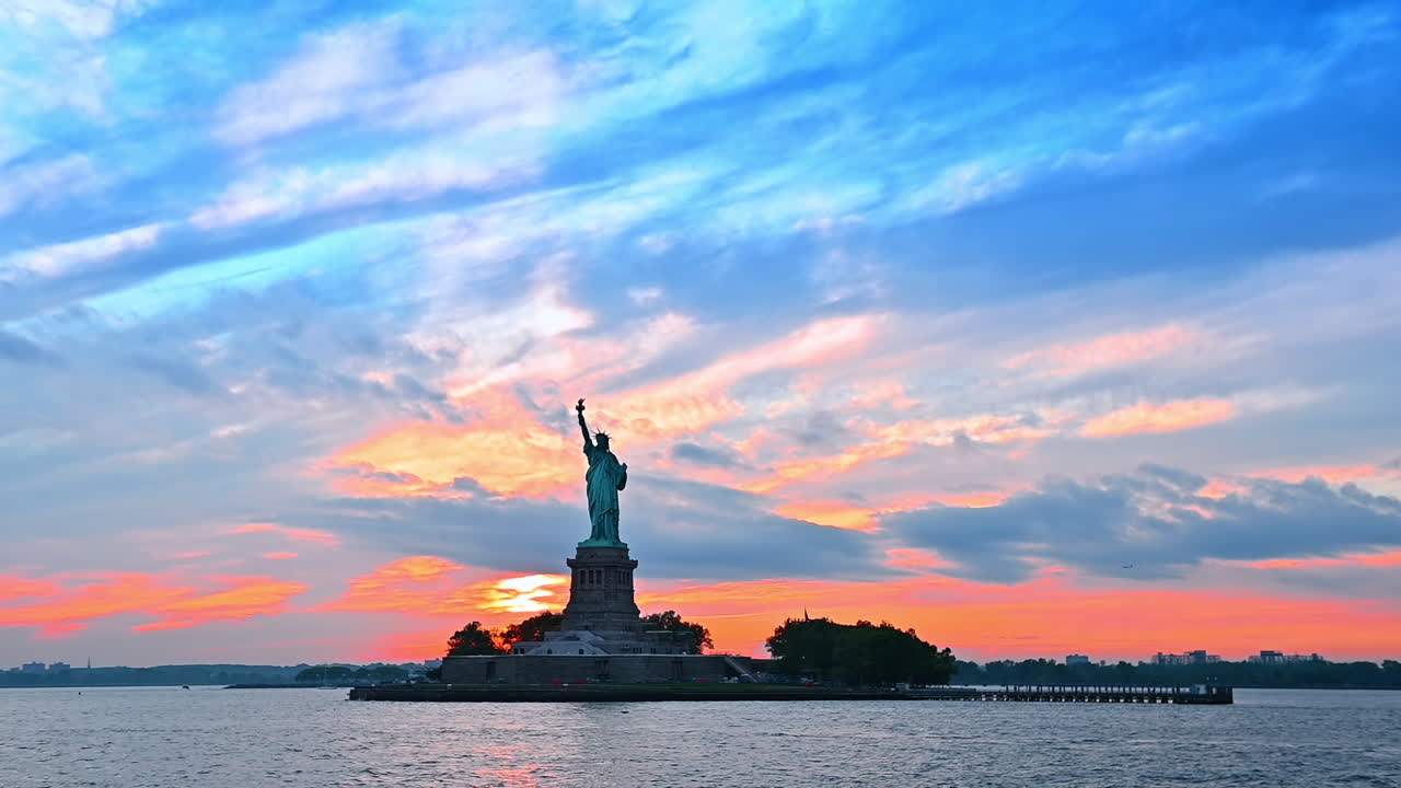 Patung Liberty yang terkenal di Pelabuhan New York. Tur sungai dengan pemandangan air saat matahari terbenam. Sudut pandang rendah
