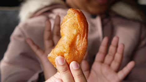 person holding a piece of donut