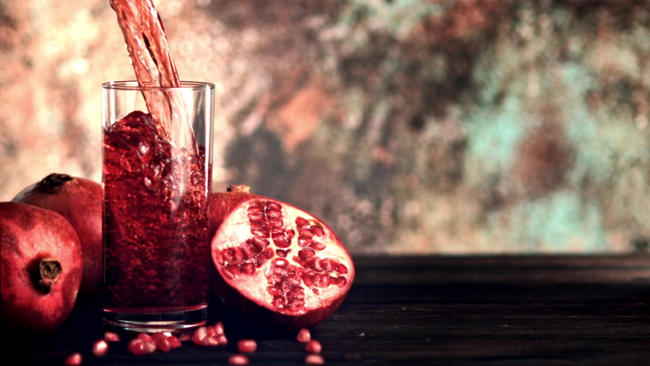 Granatæblejuice hældt i glas med hele og udskårne frugter