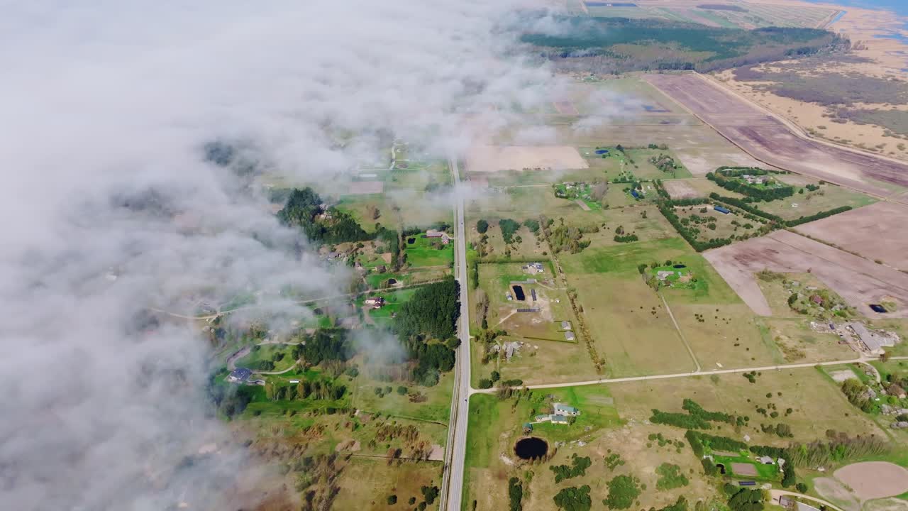 High aerial shot over highway from Lithuania to Liepaja as fog rolls from sea