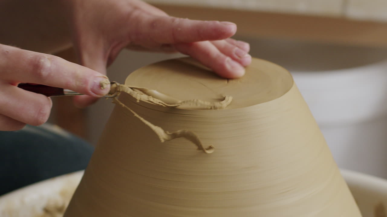 Detailed View of Hands Trimming Clay on a Pottery Wheel
