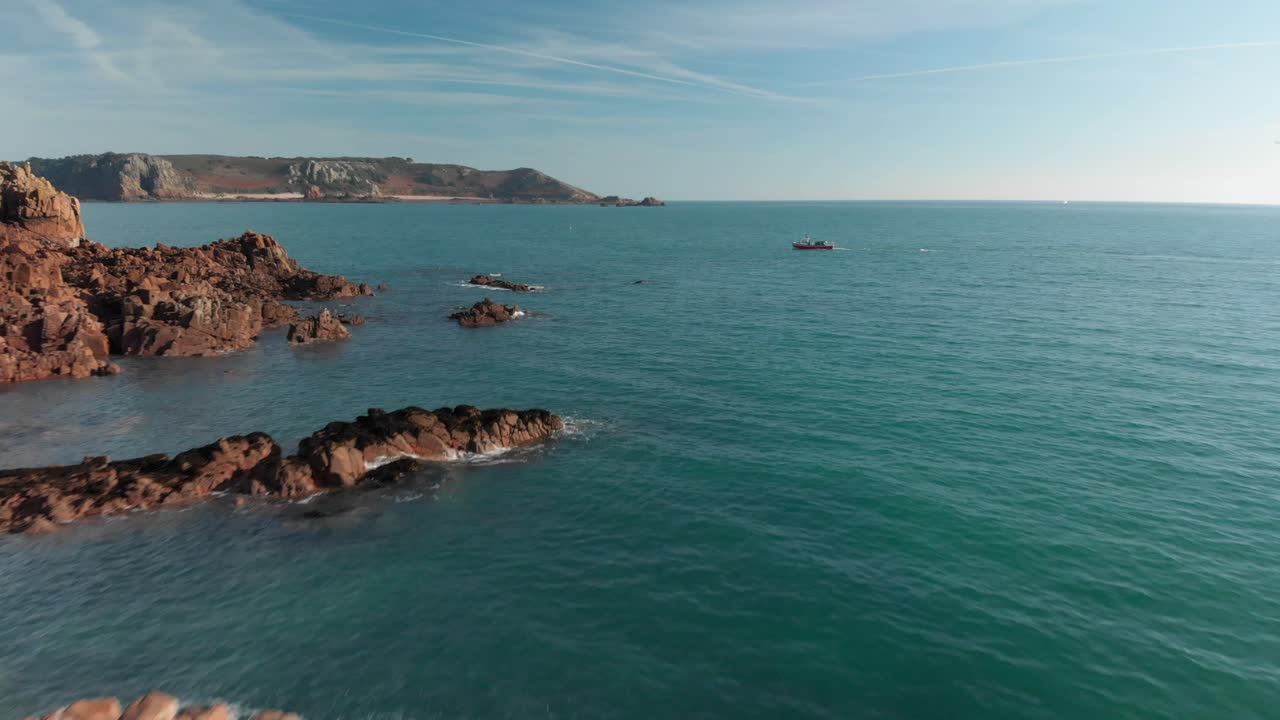 toma aérea sobre una playa de arena con rocas, moviéndose hacia atrás, alejándose del barco