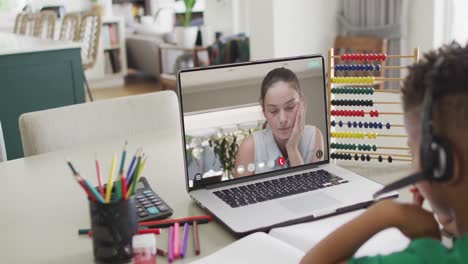 Niño-Afroamericano-Usando-Una-Computadora-Portátil-Para-Una-Lección-En-Línea-Con-Una-Maestra-Caucásica-En-La-Pantalla