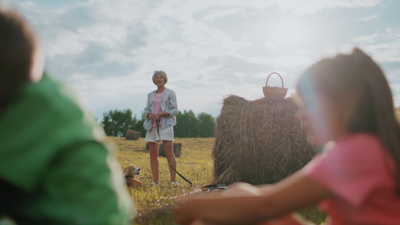 아이들은 황금빛의 빛 속에서 즐겁게 놀고, 여자는 개 줄을 들고, 야외에서 따뜻하고 반이는 빛은 놀이의 분위기를 향상시니다.