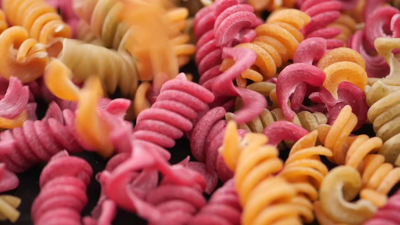 Pasta fusilli colorata non cotta in caduta.