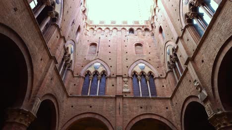 upward view from the courtyard of the palazzo pubblico and its torre del mangia at the shell-shaped square piazza del campo in siena, tuscany, italy