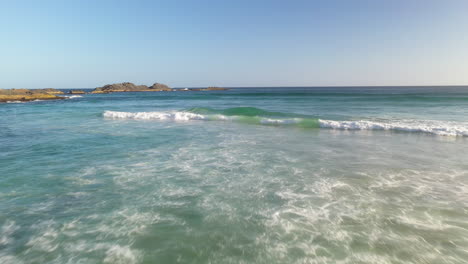 waves breaking over rocky australian beach coastline, aerial tracking view