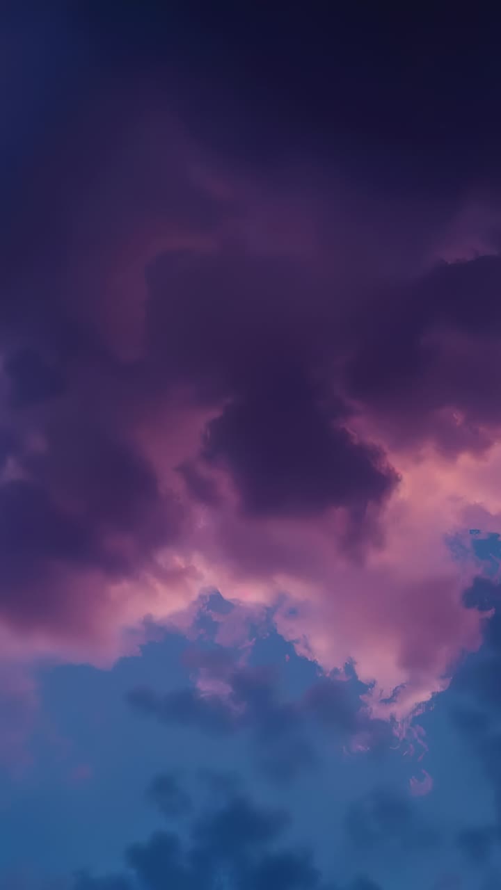 Video verticale: livelli di nuvole che si spostano aprendo il cielo blu al tramonto, mostrando nuvole viola, bordi rosa