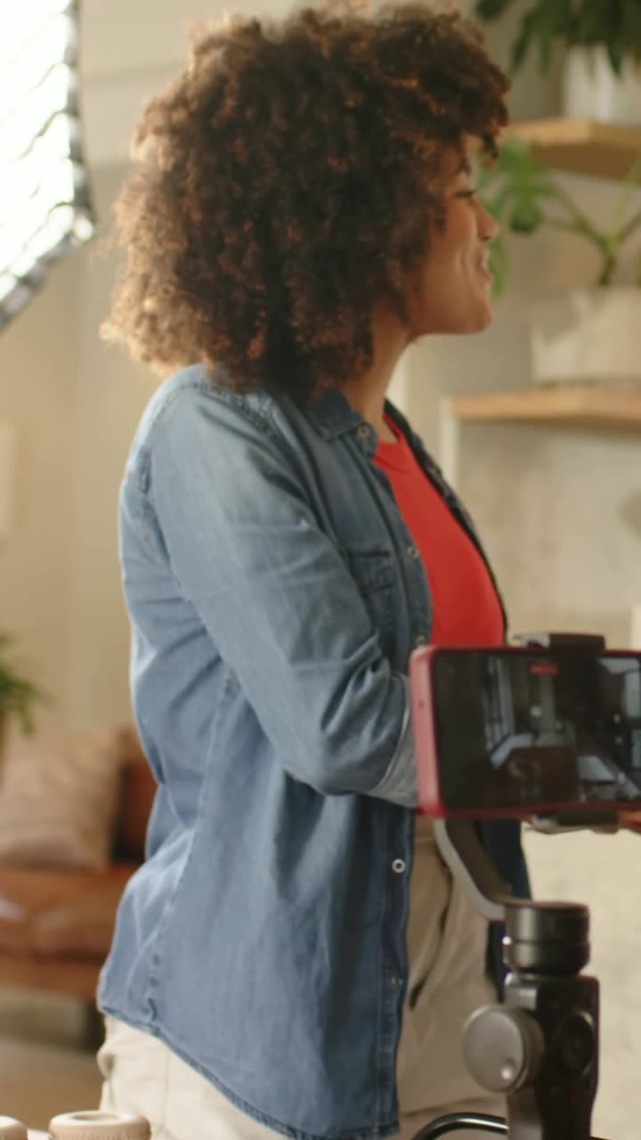 Video verticale: Ospite sorridente con top rosso che picchietta i barattoli, abbraccia un amico che torna a casa per salutarlo, filmato con gimbal.