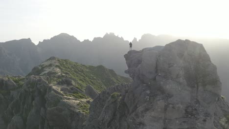 a man is standing alone on the edge of pico grande mountain in madeira during a sunrise over the beautiful landscape