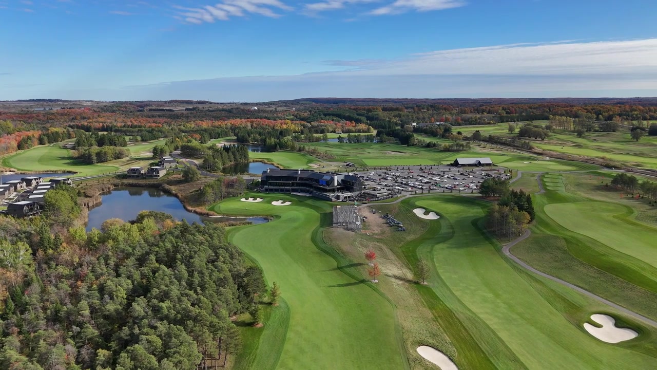 TPC Toronto in Osprey Valley mit leuchtendem Herbstlaub. Das Clubhaus, der Parkplatz und die Golfgrüns sind sichtbar. Geeignet für Reisewerbung oder Immobilienpräsentationen.