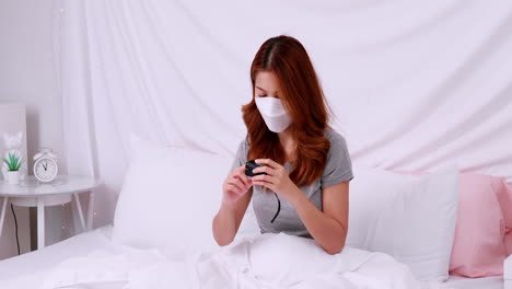 Asian-woman-with-mask-measuring-blood-oxygen-saturation-level-with-pulse-oximeter-at-home-during-the-COVID-19-pandemic-and-self-quarantine