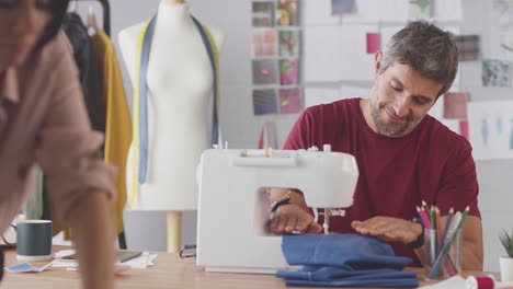 male and female fashion designers with sewing machine working in studio together