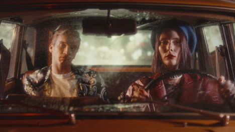 stylish woman driving vintage car at night with male passenger