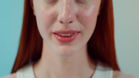 close-up of a woman with red hair and freckles smiling