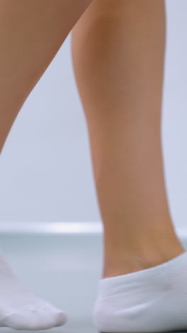 색 발목 양말을 입은 다리가 밝은 피트니스 스튜디오에서 요가 매트를 향해 고, 거울은 사람이 매트를 움직일 때 주변을 반영합니다.