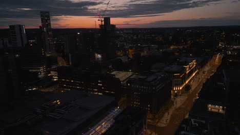 pullback establishing drone shot over leeds city centre at dawn in low light