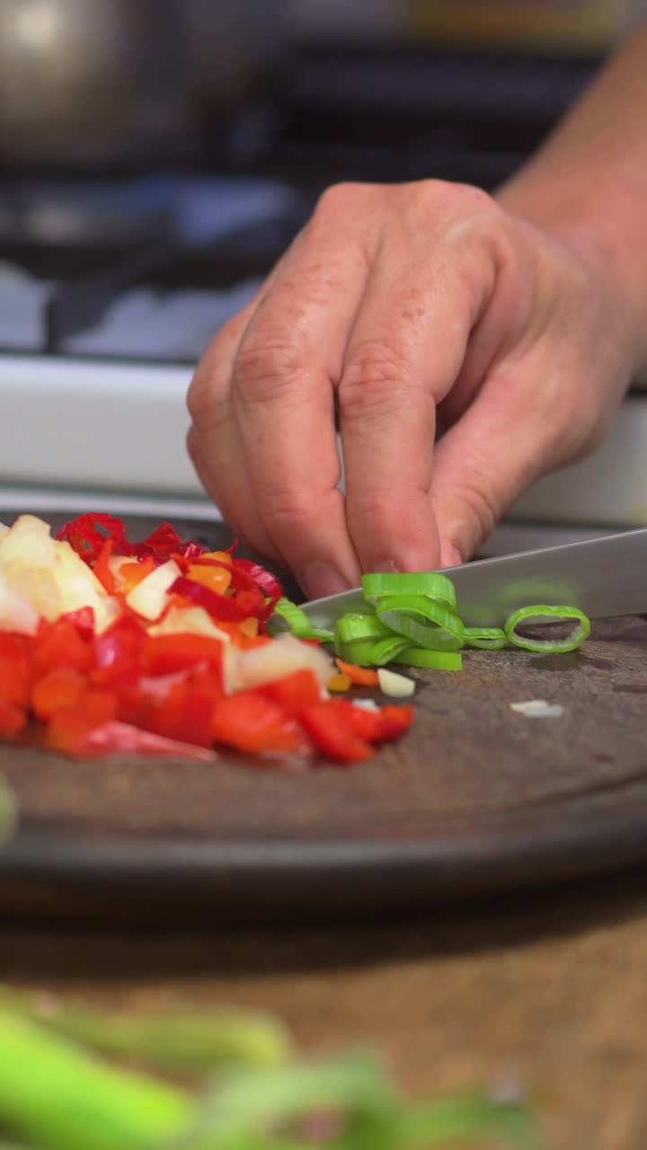 Hands cut scallions on wooden board for picadillo in traditional Latin culture