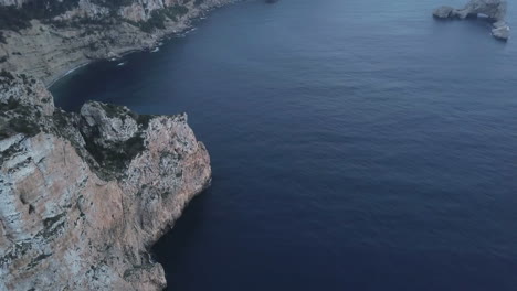 aerial - the rocky mediterranean cliffs of ibiza, spain, wide spinning shot