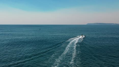 jet ski roaring across the open waters towing athlete foiling, aerial footage