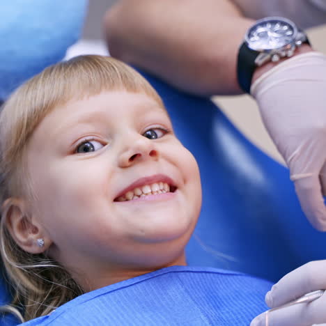 happy girl in dentist chair. portrait of a little smiling child showing her small teeth to the camera. child dentist's visit.