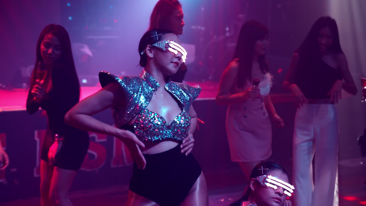 Grupo de personas bailan en la discoteca al ritmo de la música de DJ en el escenario