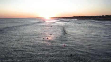 surfers catch the last waves at sunset, golden hues on the ocean, serene atmosphere