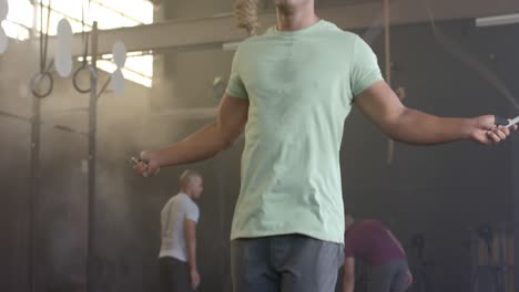 Focused-biracial-man-training-at-gym-jumping-rope,-in-slow-motion