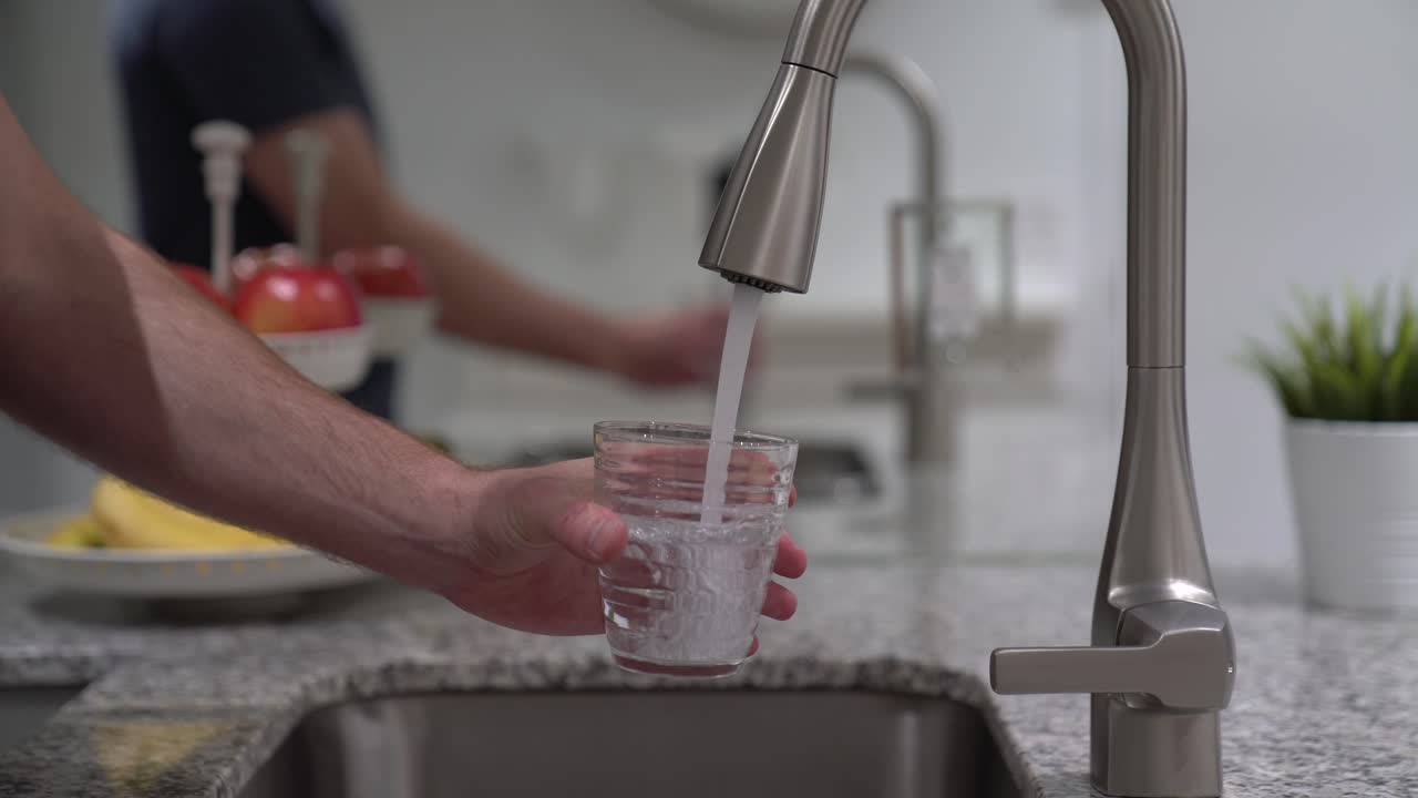 llenar el vaso con agua fresca del grifo en el fregadero en una cocina limpia para un medio ambiente sostenible