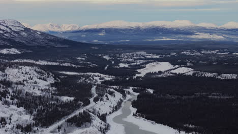 the takhini river winds through snow-covered valleys with a backdrop of majestic mountains in yukon, canada - wide shot