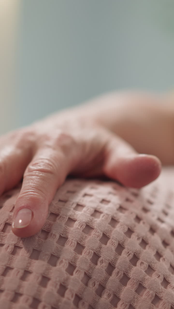 old woman runs her hand over a soft pink plaid close-up, well-groomed grandmother's hands, natural manicure