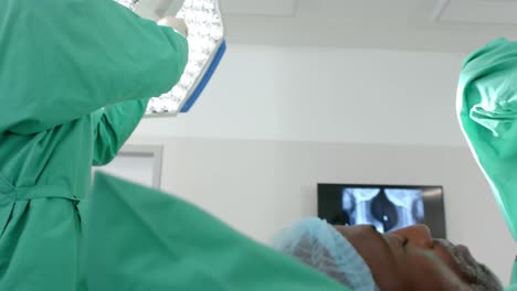 diverse surgeons wearing surgical gowns operating on patient in operating theatre, slow motion