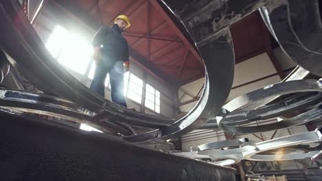 worker walking on steel parts at metal fabrication facility