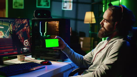 man in dimly lit apartment watching tutorial on how to finish videogame on isolated screen cellphone