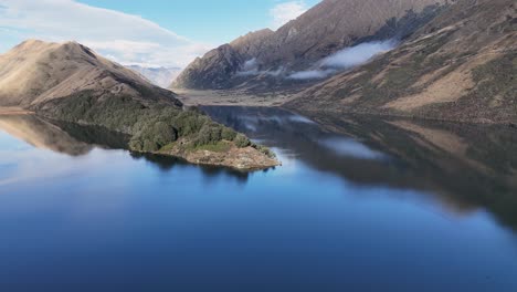 Aerial footage captures Lake Moke's tranquil waters and surrounding mountains under clear skies in Queenstown, New Zealand