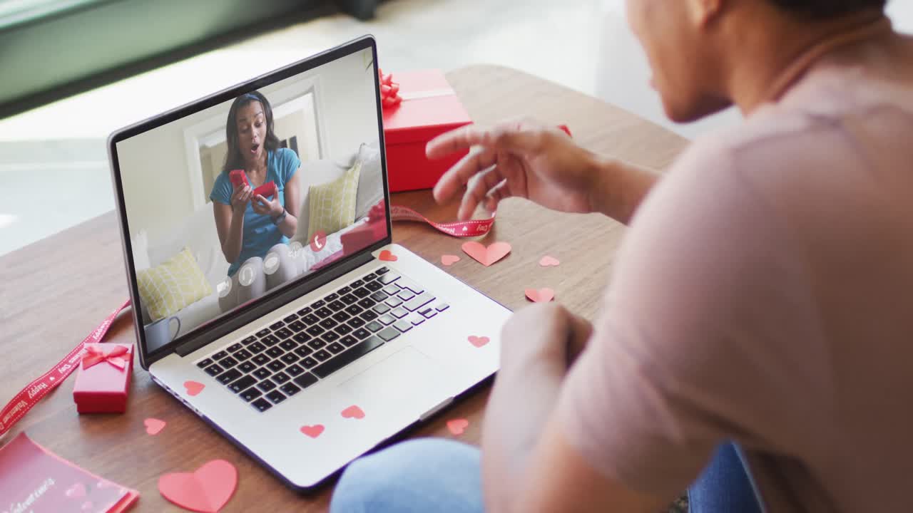 Happy african american woman opening gift and making valentine's day video call on laptop