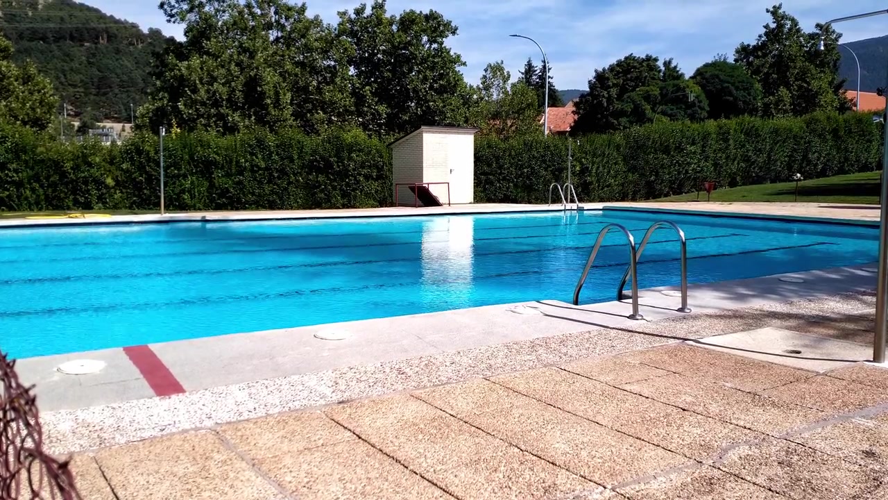 Tom udendørs swimmingpool med klart blåt vand ved siden af grønne hække på en solrig dag
