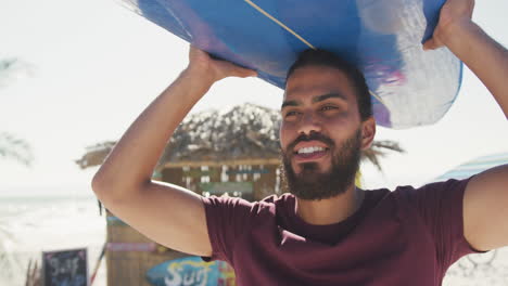 hombre mixto sosteniendo su tabla de surf en la cabeza