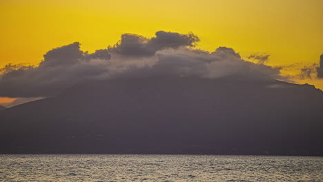 siluetas de acantilados escarpados con nubes en el lapso de tiempo como el cielo flamea con tonos ardientes