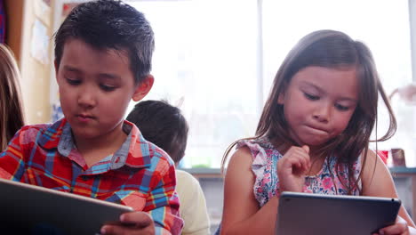 Three-pupils-using-tablets-during-lesson-at-school