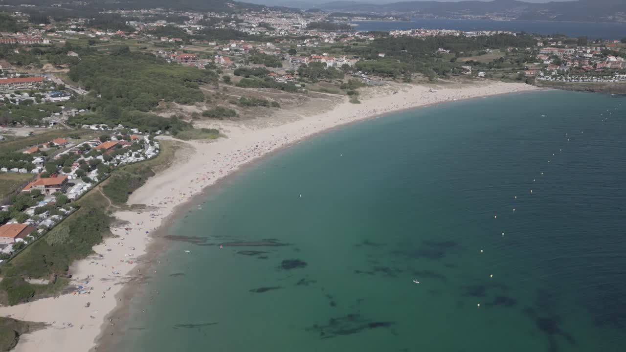 Filmato aereo grezzo di una spiaggia in un villaggio costiero con acqua cristallina color smeraldo.