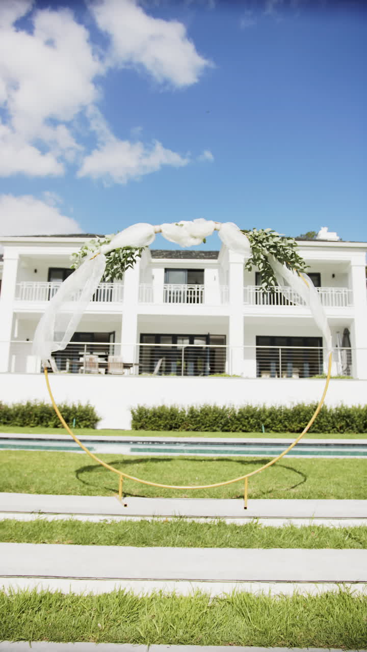 Vertical video of wedding arch with decorations and flowers in garden, in slow motion