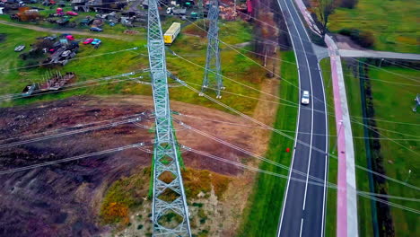 vehículos circulando por carretera asfaltada pasando por planta de transmisión de electricidad