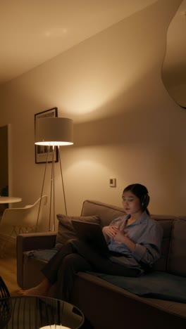 woman using a tablet on a couch at night