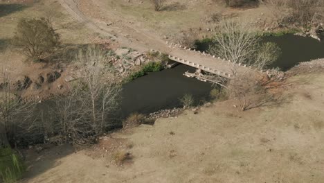drone flyover polluted river with concrete debris on edges